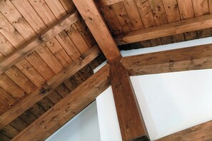 Estructura de techo de madera con vigas a la vista y paredes blancas.