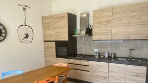 Eine moderne Küche mit Holzausstattung, einem Gaskochfeld, einer Spüle und einem Essbereich mit Holztisch und Stühlen.
