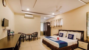 Una habitación de hotel con cama, mesita de noche, escritorio, sillas y televisión.