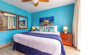 A bedroom with a large bed, two bedside tables, a ceiling fan, and artwork on the wall. - Kamaole Nalu, #504^ 2 Bedroom Condo by RedAwning (Kihei)