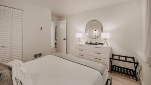 Ein Schlafzimmer mit einem Bett, einem Schminktisch mit Lampen, einem Spiegel und einem Stuhl.