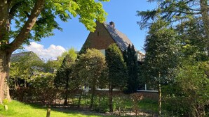 A traditional house with a sloped roof, surrounded by lush greenery and trees. - Renovated studio, near the forest and center (Bergen)