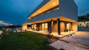 Una casa moderna de dos pisos con techo plano y ventanas grandes.