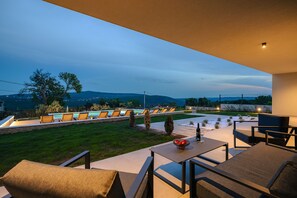 Relax in style on this serene patio, surrounded by lush greenery and a tranquil pool view.