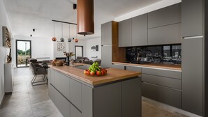 Una cocina moderna con armarios grises, encimera de madera y una isla grande con un bol de fruta.