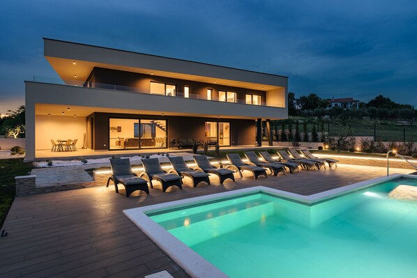 Relax and unwind in the spacious outdoor pool area with multiple sun loungers and a dining space.