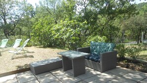 An outdoor seating area with a sofa and two chairs, a small table, and a stone-tiled floor. - Maison Avec Piscine Dans le Parc du Luberon, Chemin de Randonnée à Proximité (Gargas)