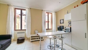 Una cocina compacta con una mesa de comedor, taburetes de bar, un refrigerador y un televisor.