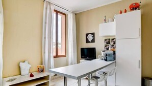 Una cocina pequeña con cubierta blanca, un refrigerador y un televisor.