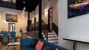Ein modernes Interieur mit einem blauen Sofa, einer Holztreppe und einem Essbereich mit blauen Stühlen.