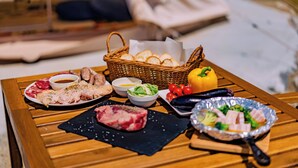 Une table en bois sur laquelle sont disposés divers aliments, notamment de la viande, des légumes et du pain.