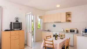 A compact kitchen with a dining area, wooden cabinets, a microwave, and a small refrigerator. - Apartments Miljan Popovic (Konavle)
