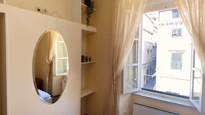 A room with a large window, a radiator, and a mirror.