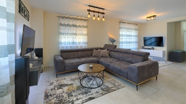A modern living room with a sectional sofa, a coffee table, and a flat-screen TV. - Brand new apartment Excellence with 3 bedrooms and 3 bathrooms (Pula)