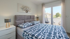 A bedroom with a bed, bedside tables, a hanging chair, and a view of the outside. - Brand new apartment Excellence with 3 bedrooms and 3 bathrooms (Pula)