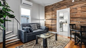 Un salon moderne avec un canapé gris, une table basse en verre et un mur d’accent en bois.