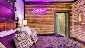 Une chambre avec un grand lit, un panneau lumineux au néon sur lequel on peut lire « Lady Bird », et un mur en bois.