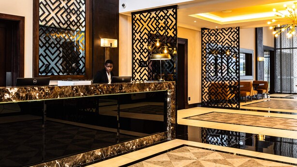 A hotel reception area with a marble counter, patterned walls, and a modern chandelier. - Premier Hotel Thohoyandou (Thohoyandou)