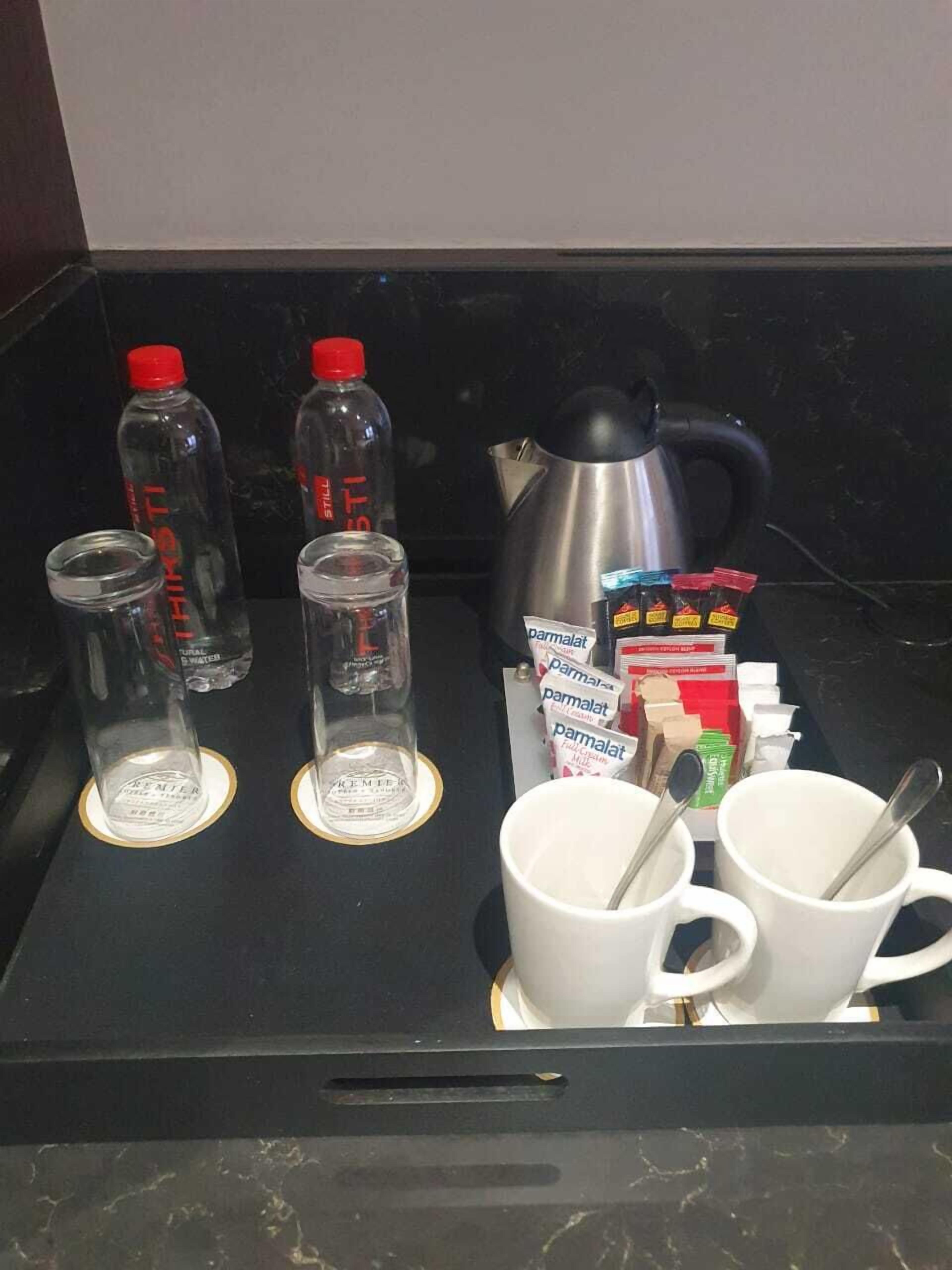 Eine Küchenarbeitsplatte mit einer Kaffeemaschine, zwei Stillwasserflaschen, zwei Gläsern und einer Packung Parmalat Milchpulver.