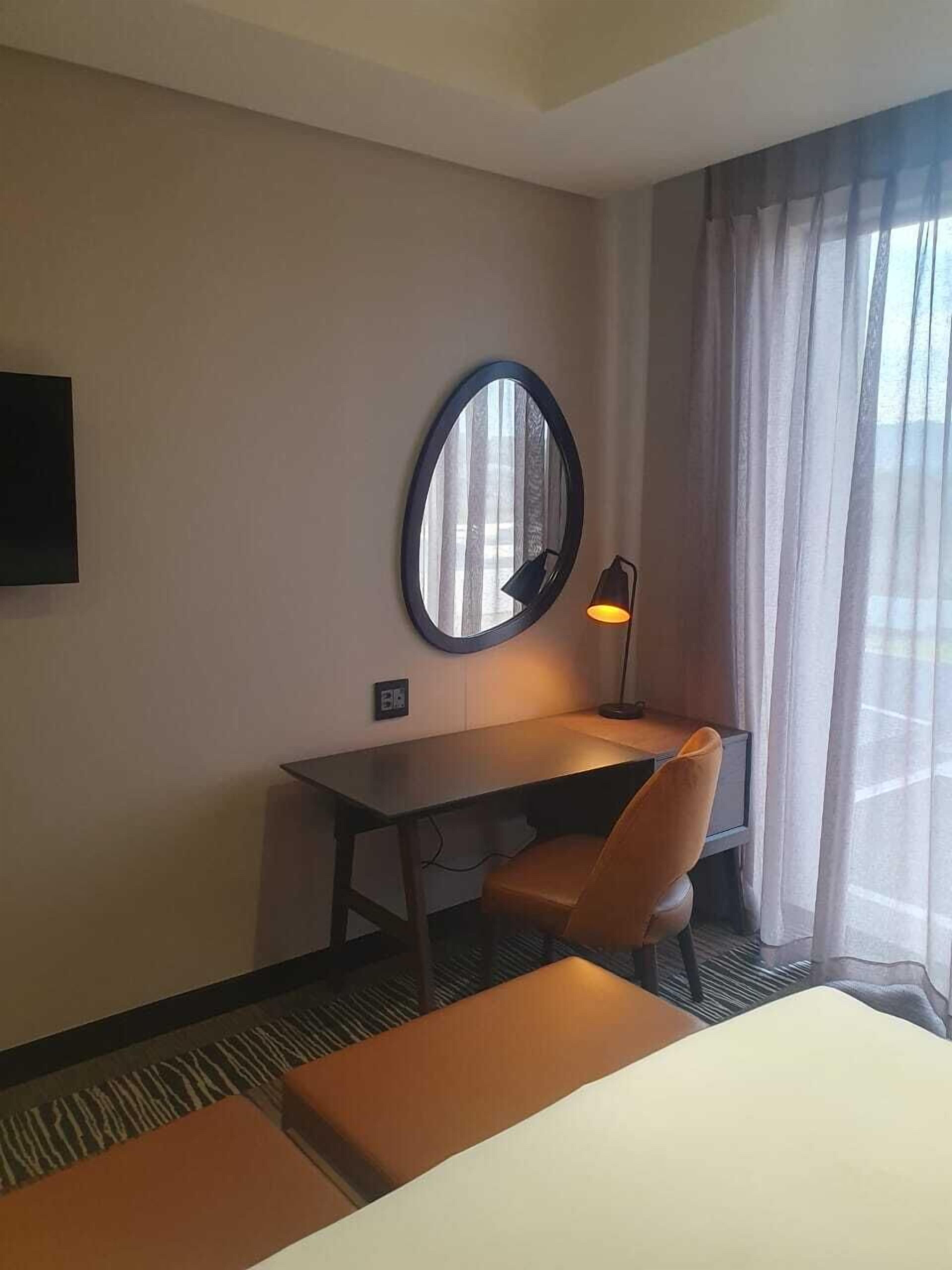 A hotel room with a desk, chair, and a bed.