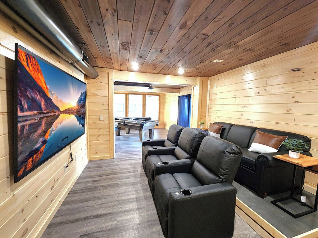 Une pièce chaleureuse avec un grand téléviseur à écran plat, un canapé en cuir et un plafond en bois.