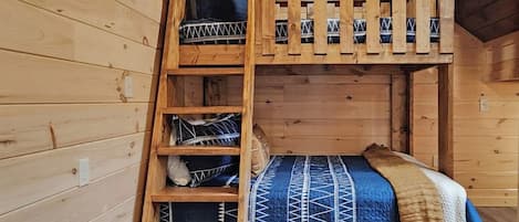 A bunk bed with a ladder, a blue patterned bedspread, and a beige blanket.
