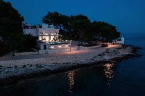 A coastal property with a pool, stone pathway, and a view of the sea. - Seafront Villa Serenita (Sumartin)