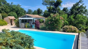 A swimming pool with a covered seating area and lush greenery. - Maison de Plain Pied à la Campagne Entre Bergerac et Villeneuve SUR LOT (Cancon)