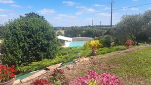 A pool area with a modern building, surrounded by lush greenery and flowering plants. - Maison de Plain Pied à la Campagne Entre Bergerac et Villeneuve SUR LOT (Cancon)