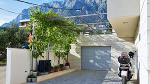 A motorcycle parked in a covered garage with a mountain backdrop. - Adria View, Apartment Dado, with pool (Makarska)