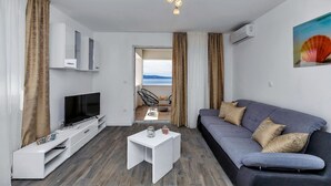 A modern living room with a flat-screen TV, white entertainment unit, grey sofa, and a small white coffee table. - Villa Legero with pool (Drašnice)