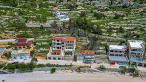 A coastal residential area with multi-story buildings, a beach, and terraced fields. - Villa Legero with pool (Drašnice)
