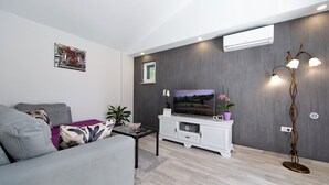 A modern living room with a grey sofa, a white entertainment unit, and a flat-screen TV. - Villa Silencio with pool (Tucepi)