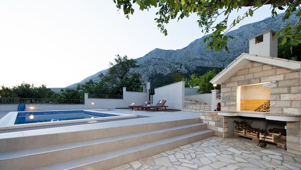A pool area with steps leading to a lounge, a stone patio, and a fireplace. - Villa Silencio with pool (Tucepi)