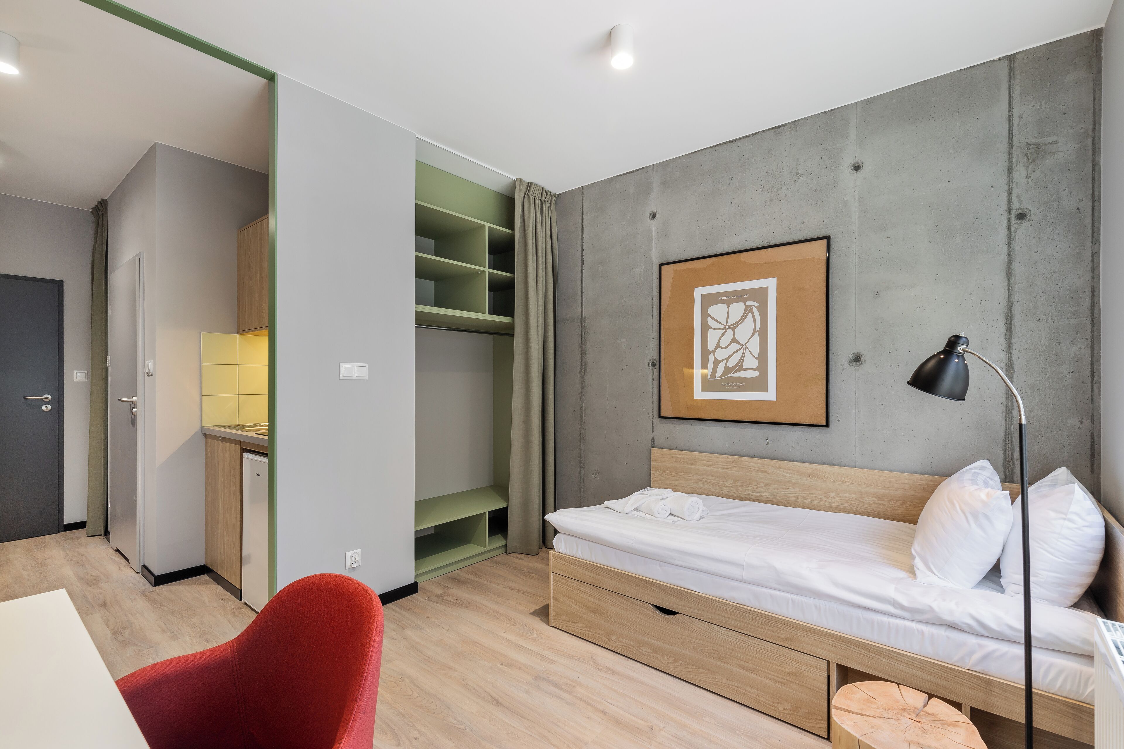 Un dormitorio moderno con una cama individual, un escritorio y una silla roja.