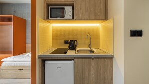 A compact kitchen with a microwave, sink, and a compact refrigerator. - NextDoor Apartments (Kraków)