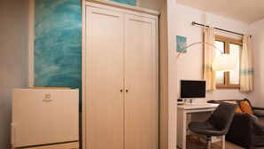 Une pièce comprenant un placard, un bureau avec un ordinateur, une chaise et un canapé.