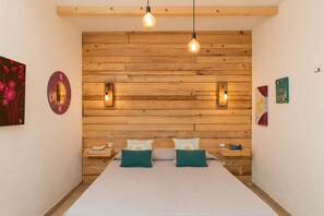 Un dormitorio con cabecera de madera, dos mesitas de noche y una cama con almohadas color turquesa.