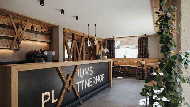 A modern bar area with a wooden counter, bar stools, and a chalkboard sign. - Rienz Apartment – Farm Stay in Nature and Relaxation (Naz-Sciaves)