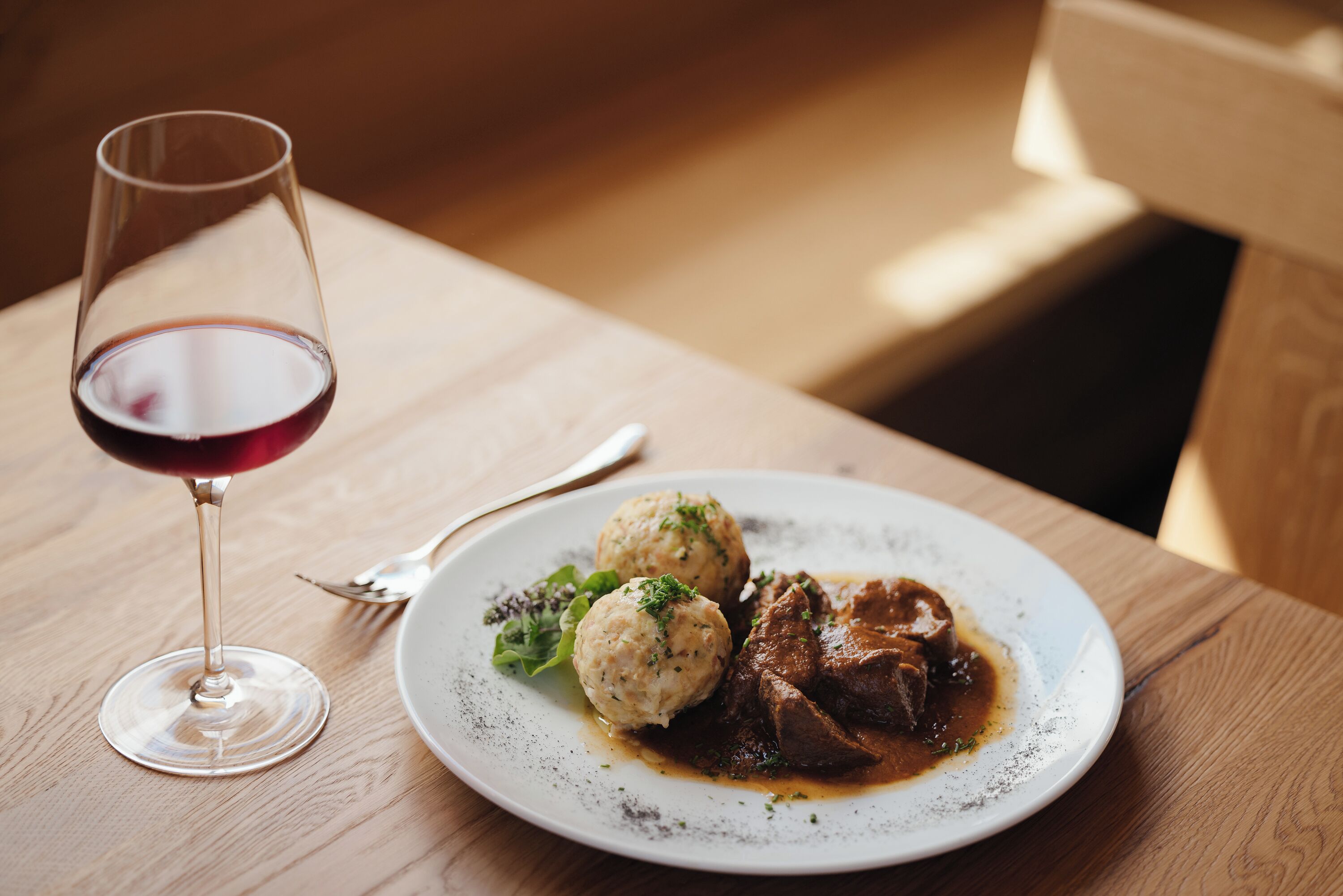 A plate of food with a glass of red wine on a wooden table.