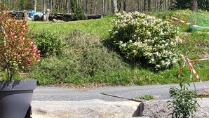 A stone pathway leading through a landscaped area with a large planter and a bush with white flowers. - L'évasion au Chalet de Fraize Avec vue Imprenable,équipé de Vélos Électriques (Fraize)