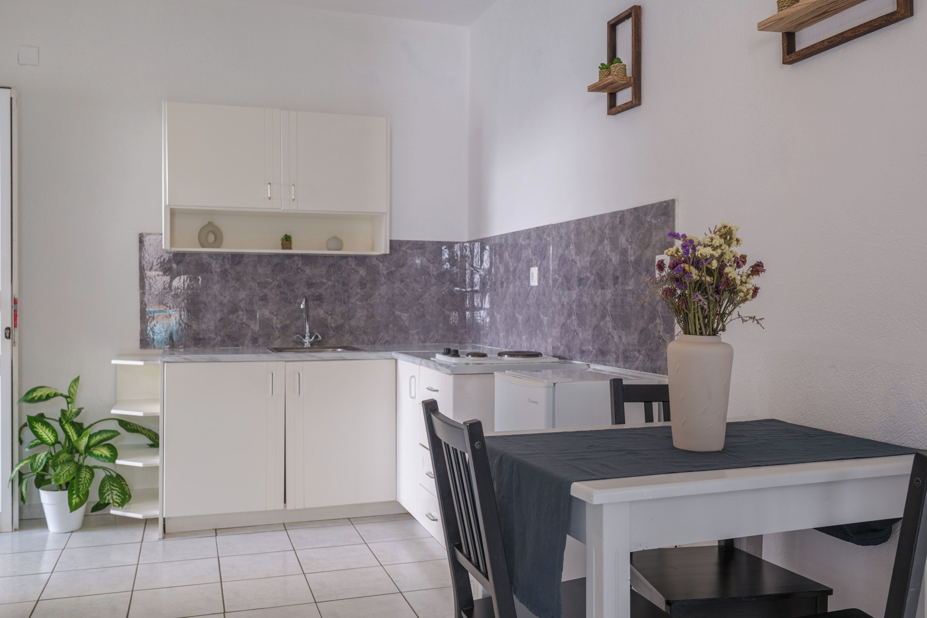 A modern kitchen with white cabinets, a marble backsplash, and a dining area with a table and chairs.