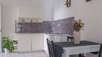 A modern kitchen with white cabinets, a marble backsplash, and a dining area with a table and chairs.