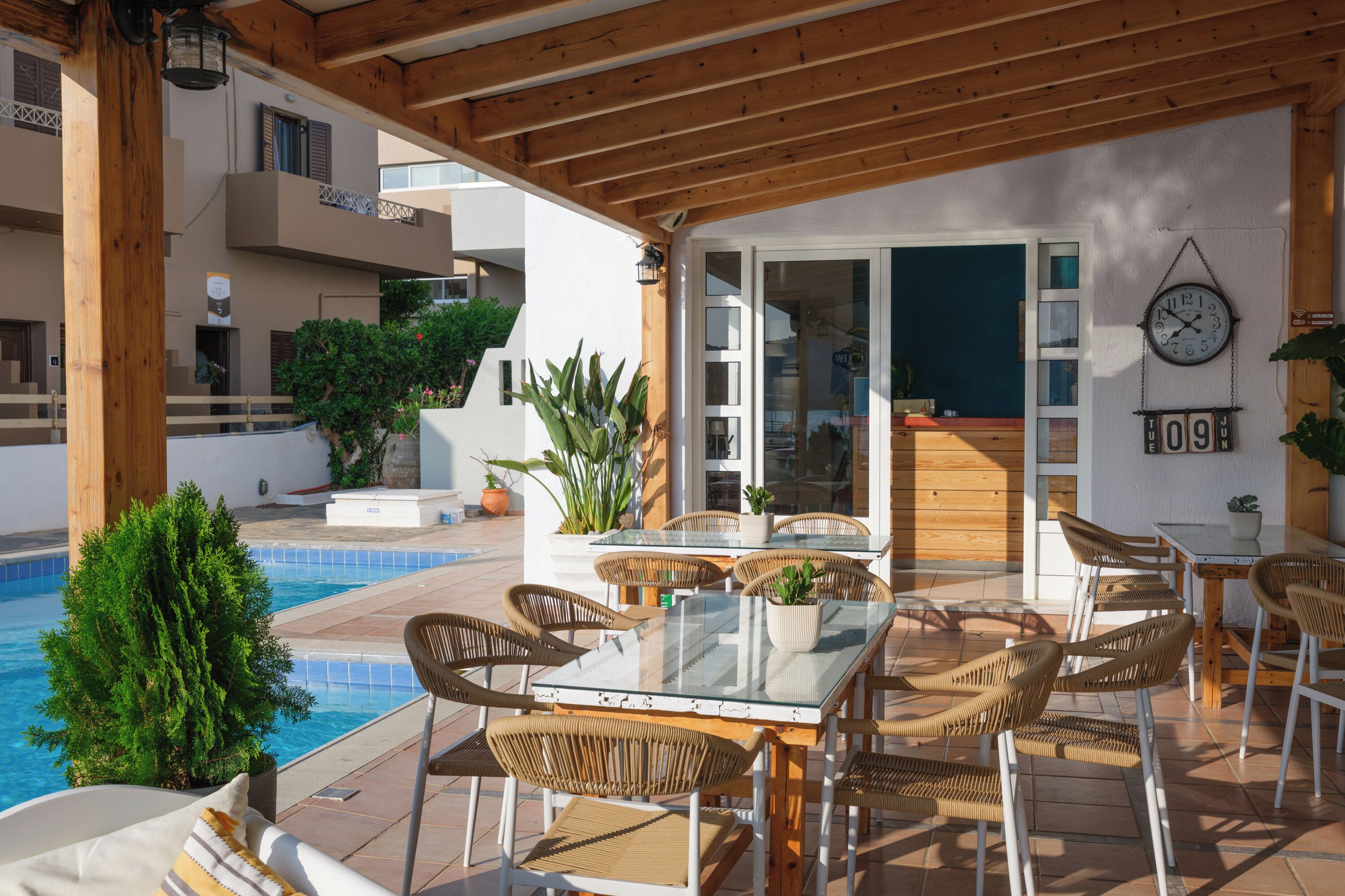 Un espacio al aire libre cubierto con una piscina, sillas de mimbre y una mesa.
