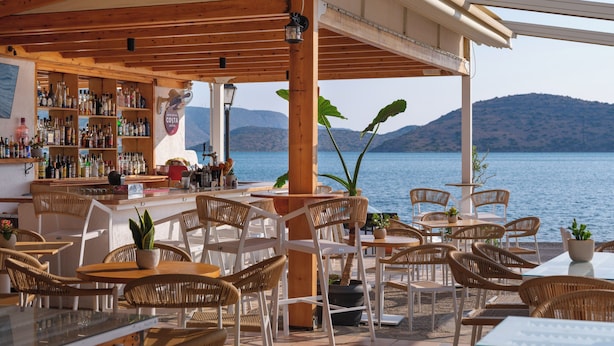 Een strandbar met rieten meubels en uitzicht op zee.