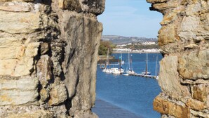 Un arc en pierre menant à une marina où sont amarrés des bateaux.