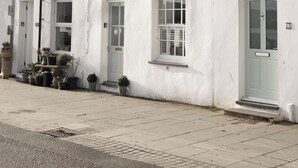 A row of white buildings with multiple windows and doors, some with shutters, and a visible chimney on the roof. - Water View Cottage, Water View Cottage (Conwy)