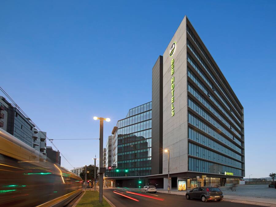 Um hotel moderno com fachada imponente, grandes janelas e entrada bem iluminada.