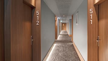 Pasillo de hotel con puertas de madera, numeradas 512 y 511, y una alfombra estampada.
