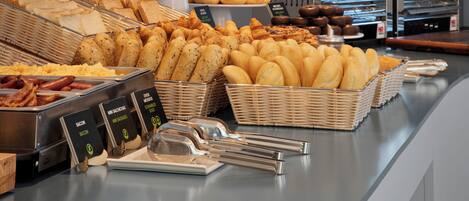 Um buffet com diversos alimentos, incluindo pães, doces e carnes.